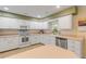 White kitchen with ample counter space, updated appliances, and a corner sink at 299 W Hickory Ave, Oak Hill, FL 32759