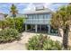 Two-story beach house with a balcony, driveway, and lush landscaping at 6368 S Atlantic Ave, New Smyrna Beach, FL 32169