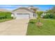 Tan house with white garage door, landscaping, and palm tree at 51 Sun Dunes Cir, Ponce Inlet, FL 32127