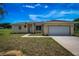 Front view of a single-story house with a beige exterior, two-car garage, and landscaped lawn at 15190 Cr-565A, Clermont, FL 34711
