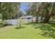Spacious backyard with a large grassy area, white fence, and mature oak trees at 1319 Orange Tree Dr, Edgewater, FL 32132