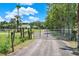 Gravel driveway entrance with metal gate and fencing at 3650 Pepper Ln, New Smyrna Beach, FL 32168