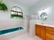 Main bathroom with teal jacuzzi tub, walk-in shower, and wood vanity at 1780 Otisco Way, Winter Springs, FL 32708