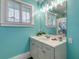 Light teal bathroom with white vanity, updated fixtures, and decorative shower curtain at 412 S Peninsula Ave, New Smyrna Beach, FL 32169