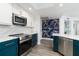 Modern kitchen with teal cabinets, quartz countertops, and statement tropical wallpaper at 241 Riverside Dr # 2007, Holly Hill, FL 32117