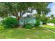 Quaint light green house with a lush lawn, mature trees, and driveway at 1206 S Riverside Dr, New Smyrna Beach, FL 32168