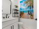 Stylish bathroom with white vanity, beach-themed art, and marble floor at 224 Condict Dr, New Smyrna Beach, FL 32169