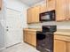 View of kitchen with black appliances and wood cabinets at 679 Mount Olympus Blvd, New Smyrna Beach, FL 32168