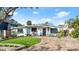 Quaint mid-century home with lush landscaping and a brick driveway at 624 S Pine St, New Smyrna Beach, FL 32169