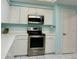 Kitchen with white cabinets, stainless steel appliances, and microwave at 200 S Riverside Dr # 2010, New Smyrna Beach, FL 32168