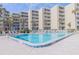 Large community pool surrounded by palm trees and lounge chairs at 2401 S Atlantic Ave # C206, New Smyrna Beach, FL 32169