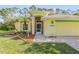 Front view of a yellow house with a teal door and landscaping at 2853 Turnbull Estates Dr, New Smyrna Beach, FL 32168