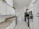 Long kitchen with white cabinets, black appliances, and grey countertops at 2853 Turnbull Estates Dr, New Smyrna Beach, FL 32168