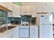 White kitchen with teal backsplash, microwave, stove, and refrigerator at 3509 S Atlantic Ave # 108 & 109, New Smyrna Beach, FL 32169