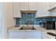 White kitchen cabinets and teal backsplash, with sink and countertop at 3509 S Atlantic Ave # 108 & 109, New Smyrna Beach, FL 32169