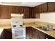 Galley kitchen with dark wood cabinets and white appliances at 4175 S Atlantic Ave # 2150, New Smyrna Beach, FL 32169