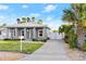 Single-story home with a light blue door, landscaped front yard, driveway, and a metal roof at 833 E 26Th Ave, New Smyrna Beach, FL 32169