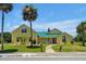 Beautiful yellow house with green metal roof, palm trees, and walkway at 886 Matthews Ave, New Smyrna Beach, FL 32169