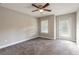 Bedroom with gray carpet, ceiling fan, and door leading to the backyard at 3414 Medici Blvd, New Smyrna Beach, FL 32168