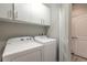 Laundry room with white Whirlpool washer and dryer and white cabinets at 3414 Medici Blvd, New Smyrna Beach, FL 32168