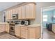 Kitchen with wood cabinetry, stainless steel appliances, and doorway to laundry area at 3769 Fiano Dr, Port Orange, FL 32129
