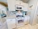 White kitchen with granite countertops, microwave, and electric range at 4208 Sun Village Ct # 4208, New Smyrna Beach, FL 32169