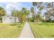 Landscaped backyard with a gravel path, lush lawn, and a studio at 4946 Halifax Dr, Port Orange, FL 32127