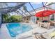 Inviting pool area with a screened enclosure, patio furniture, and red umbrella at 4946 Halifax Dr, Port Orange, FL 32127