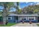 Front view of a blue brick home with white trim, a covered porch, rocking chairs, and landscaping at 805 E 17Th Ave, New Smyrna Beach, FL 32169