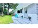 Front exterior with gray and white siding, teal chair, and lush green lawn at 812 Faulkner St, New Smyrna Beach, FL 32168