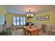 Dining room with chandelier, table, and chairs, and large windows with shutters at 839 Fairway Dr, New Smyrna Beach, FL 32168