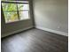 Bright bedroom with dark laminate flooring and a window at 2512 Woodgate Blvd # 104, Orlando, FL 32822