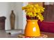 Yellow flowers in an orange vase on a wooden table at 1375 Tuscana Ln # 1308, Davenport, FL 33896