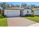 Curb appeal of one-story home with gray exterior, and brick driveway at 28078 Poppy Ct, Leesburg, FL 34748