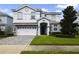 Two-story house with a white exterior, gray stone accents, and a three-car garage at 8911 Stinger Dr, Champions Gate, FL 33896