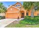 Two-story house with orange exterior and landscaping at 742 Orange Cosmos Blvd, Davenport, FL 33837