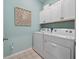 Laundry room with white washer and dryer, cabinets and light teal walls at 4413 Lions Gate Ave, Clermont, FL 34711