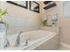 Bathroom with an oval bathtub, tile surround, and floating shelves at 3466 Halsway Dr, Orlando, FL 32824