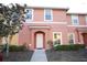 Two-story townhome with peach-colored exterior, landscaping, and walkway at 3004 Red Ginger Rd, Kissimmee, FL 34747