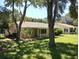 Rear view of a tan house with a covered patio and lush lawn at 32525 Oak Park Dr, Leesburg, FL 34748