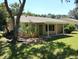 Tan house exterior with covered patio and lawn at 32525 Oak Park Dr, Leesburg, FL 34748
