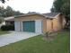 Tan house with a two-car garage and nicely landscaped front yard at 32525 Oak Park Dr, Leesburg, FL 34748
