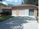 Tan house with a double garage and landscaped yard at 32525 Oak Park Dr, Leesburg, FL 34748