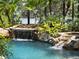 Serene waterfall feature cascading into a swimming pool at 1911 Lake Markham Preserve Trl, Sanford, FL 32771