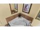 Corner jacuzzi tub with tiled surround and decorative mirror at 6312 Buford St # 303, Orlando, FL 32835