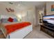 Spacious bedroom with white bed frame, orange blanket, and TV at 3587 Casalta Cir, New Smyrna Beach, FL 32168
