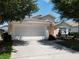 Tan two-story house with white garage door and landscaped yard at 114 Castlemain Cir, Davenport, FL 33897