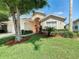 One-story house with a lush green lawn and mature trees at 114 Castlemain Cir, Davenport, FL 33897