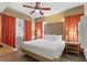 King-size bed, ceiling fan, and orange curtains in the main bedroom at 12544 Floridays Resort Dr # 503-B, Orlando, FL 32821