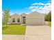 Tan house with two-car garage, landscaping, and driveway at 6368 Chorus Dr, Mascotte, FL 34753